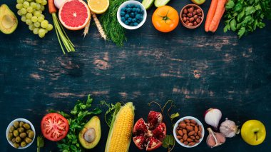 Sağlıklı gıda seçimi yeme temiz: sebze, meyve, fındık, çilek ve mantar, maydanoz, baharatlar. Siyah bir arka plan üzerinde. Metin için boş alan.