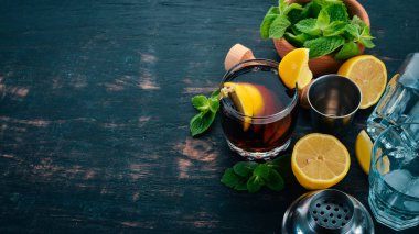 Viski, limon ve nane alkollü kokteyl. Rom-kola. Brandy. Siyah ahşap arka plan üzerinde. Metin için boş alan.