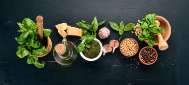 Fesleğen pesto sosu hazırlarken. Fesleğen, parmesan peyniri, zeytinyağı. Üstten görünüm. Siyah ahşap arka plan üzerinde. Metin için boş alan.