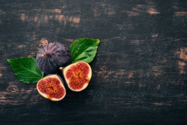 Taze incir yaprakları üzerinde siyah ahşap bir masa ile. Metin için özgür yer. Üstten görünüm.