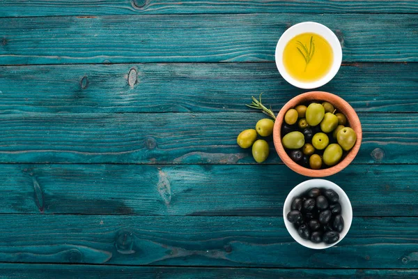 一组橄榄橄榄油和迷迭香 绿色橄榄和黑橄榄 在蓝色的木质背景上 文本的可用空间 — 图库照片