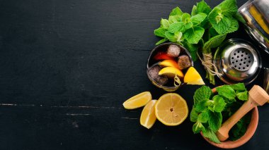 Viski, limon ve nane alkollü kokteyl. Rom-kola. Brandy. Siyah ahşap arka plan üzerinde. Metin için boş alan.