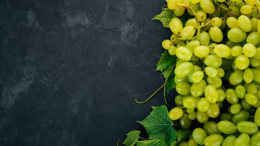 Yeşil üzüm üzüm yaprakları taş bir tablo ile. Üstten görünüm. Metin için boş alan.