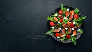 Taze salata incir ile roka yaprakları, kiraz domates ve peynir. Metin için özgür yer. Üstten görünüm.