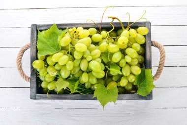 Beyaz üzüm mezarda bir beyaz tahta masada. Üzüm yaprakları. Üstten görünüm. Metin için boş alan.