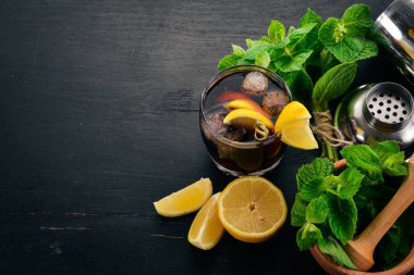Viski, limon ve nane alkollü kokteyl. Rom-kola. Brandy. Siyah ahşap arka plan üzerinde. Metin için boş alan.