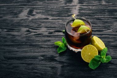Cuba libre kokteyl cam. Limon, nane. Siyah ahşap arka plan üzerinde. Metin için boş alan.