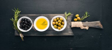 Zeytin ve zeytin yağı ve biberiye kümesi. Yeşil zeytin ve zeytin. Siyah ahşap arka plan üzerinde. Metin için boş alan.