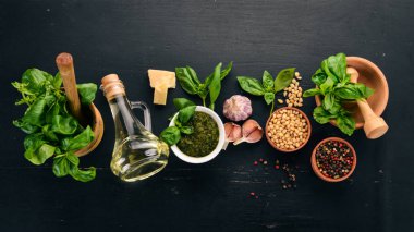 Fesleğen pesto sosu hazırlarken. Fesleğen, parmesan peyniri, zeytinyağı. Üstten görünüm. Siyah ahşap arka plan üzerinde. Metin için boş alan.