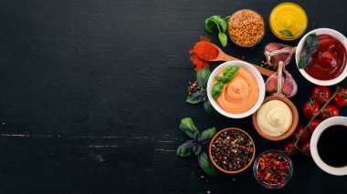 Soslar siyah bir ahşap arka plan ayarla. Ketçap, mayonez, hardal, soya sosu, Barbekü sos, biber ve baharat. Üstten görünüm. Metin için boş alan.