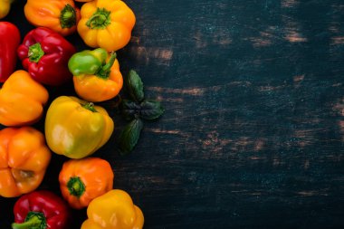 Taze renkli kırmızı biber. Üstten görünüm. Siyah ahşap arka plan üzerinde. Metin için boş alan.