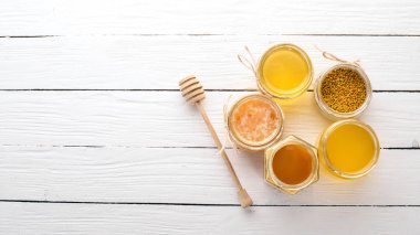 Arı ürünleri ve bal beyaz ahşap zemin üzerinde kümesi. Metin için özgür yer. Üstten görünüm.