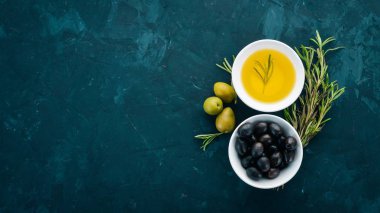 Zeytin ve zeytin yağı ve biberiye kümesi. Yeşil zeytin ve zeytin. Siyah taş arka plan üzerinde. Metin için boş alan.