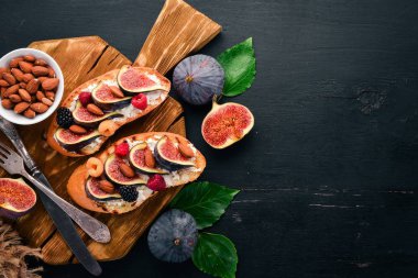 İncir, yaban meyveleri ve peynirli sandviç. Eski arka plan üzerinde. Tatlı. Metin için özgür yer. Üstten görünüm.