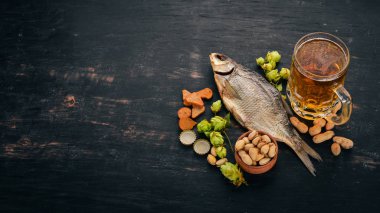 Bira ve aperatifler bir seçim. Light bira, karanlık bira, canlı bira. Siyah ahşap arka plan üzerinde. Metin için özgür yer. Üstten görünüm.