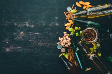 Bira ve aperatifler bir seçim. Light bira, karanlık bira, canlı bira. Siyah ahşap arka plan üzerinde. Metin için özgür yer. Üstten görünüm.