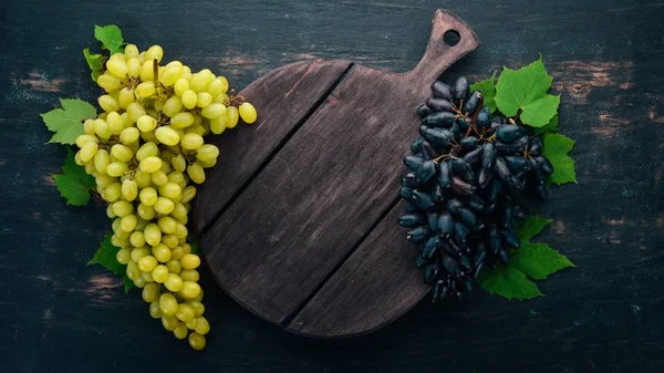 Uvas Negras Blancas Una Tabla Madera Sobre Viejo Fondo Madera —  Fotos de Stock