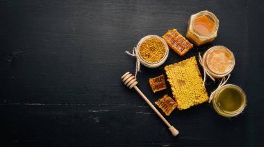 Bal ve arı ürünleri kümesi. Petek tatlım. Siyah ahşap arka plan üzerinde. Metin için özgür yer. Üstten görünüm.