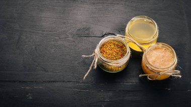 Bal ve arı ürünleri kümesi. Petek tatlım. Siyah ahşap arka plan üzerinde. Metin için özgür yer. Üstten görünüm.