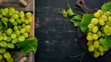 Taze yeşil üzüm üzüm yaprakları ile. Üstten görünüm. Siyah ahşap arka plan üzerinde. Metin için boş alan.