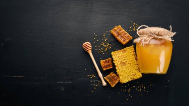 Kavanozda bal ve bal peteği. Siyah tahta bir arka planda. Metin için boş alan. Üst görünüm.