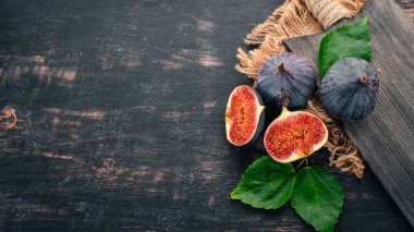 İncir ahşap bir gemide. Dilim incir. Karanlık bir arka plan üzerinde. Metin için özgür yer. Üstten görünüm.