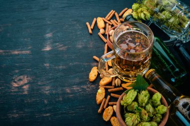 Bira ve aperatifler bir seçim. Light bira, karanlık bira, canlı bira. Siyah ahşap arka plan üzerinde. Metin için özgür yer. Üstten görünüm.