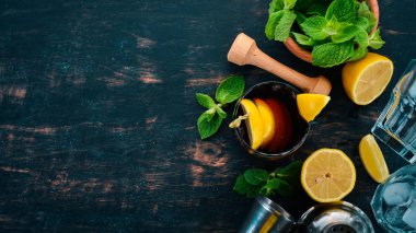 Viski, limon ve nane alkollü kokteyl. Rom-kola. Brandy. Siyah ahşap arka plan üzerinde. Metin için boş alan.