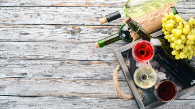 Kırmızı ve beyaz şarap şişeleri ve gözlük kümesi. Üzüm. Beyaz ahşap zemin üzerinde. Metin için özgür yer. Üstten görünüm.