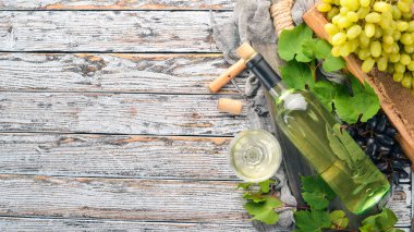 Bir cam ve üzüm ile bir şişe beyaz şarap. Beyaz ahşap zemin üzerinde. Metin için özgür yer. Üstten görünüm.