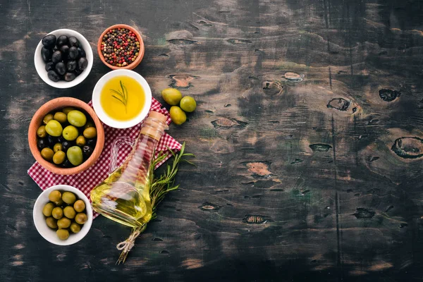 一组橄榄橄榄油和迷迭香 绿色橄榄和黑橄榄 在黑色的木质背景 文本的可用空间 — 图库照片