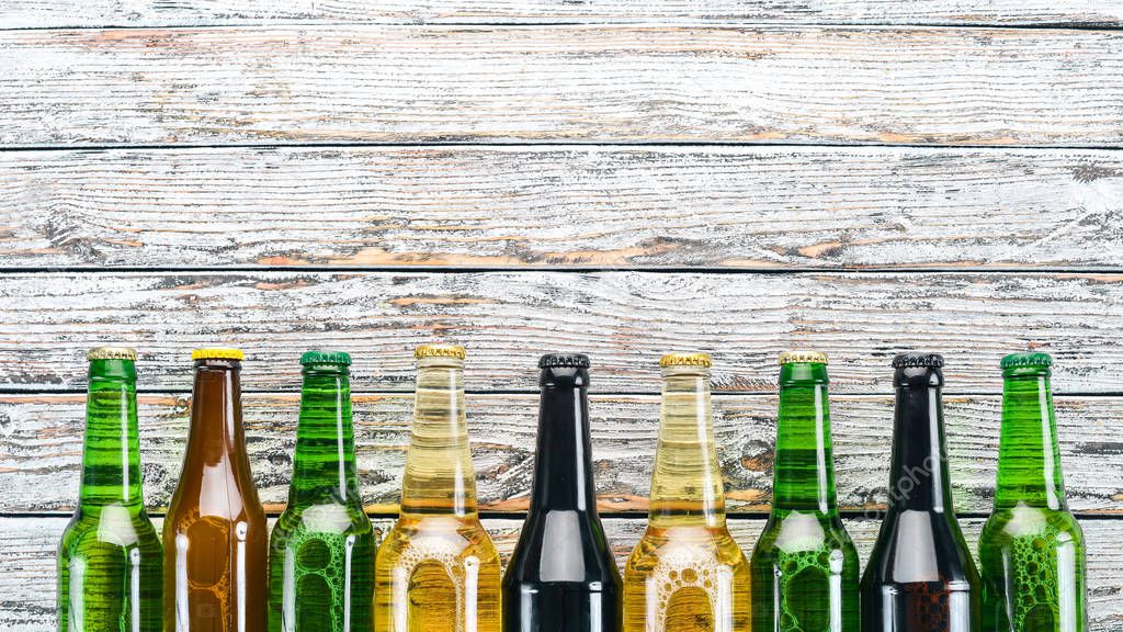 A large selection of beer bottles. On a white wooden table. Free space for text. Top view.