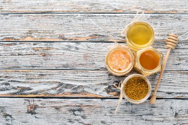 Arı ürünleri ve bal beyaz ahşap zemin üzerinde kümesi. Metin için özgür yer. Üstten görünüm.