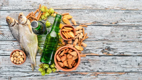 Background beer and snacks. Hops, beer, chips, nuts. On a white wooden background. Free space for text. Top view.