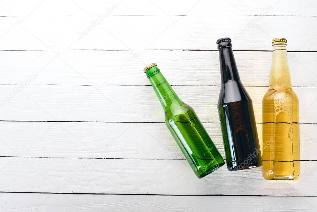 A large selection of beer bottles. On a white wooden table. Free space for text. Top view.