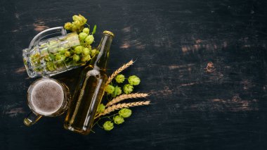 Bira ve siyah bir ahşap zemin üzerine taze şerbetçiotu. Metin için özgür yer. Üstten görünüm.