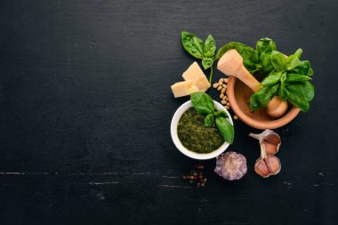 Fesleğen pesto sosu hazırlarken. Fesleğen, parmesan peyniri, zeytinyağı. Üstten görünüm. Siyah ahşap arka plan üzerinde. Metin için boş alan.