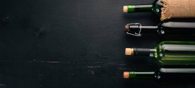 Kırmızı ve beyaz şarap şişeleri ve gözlük kümesi. Üzüm. Siyah ahşap arka plan üzerinde. Metin için özgür yer. Üstten görünüm.