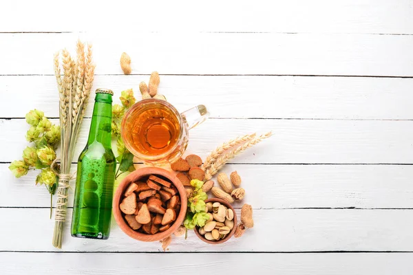 A bottle of beer. Hops, beer, chips, nuts. On a white wooden background. Free space for text. Top view.