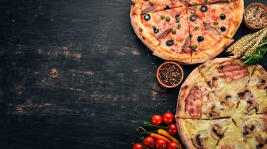 Pizza kümesi. Siyah ahşap arka plan üzerinde. Metin için özgür yer. Üstten görünüm.