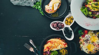 Bir dizi yemek. Shakshuka, omlet, avokado salata, haşlanmış yumurta ile sandviç. Ahşap bir arka plan üzerinde. Metin için özgür yer. Üstten görünüm.