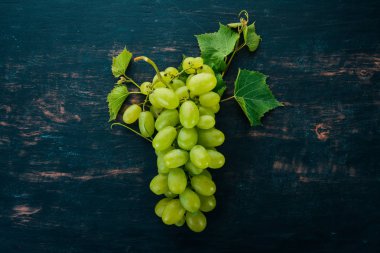 Taze yeşil üzüm üzüm yaprakları ile. Üstten görünüm. Siyah ahşap arka plan üzerinde. Metin için boş alan.