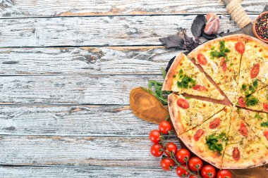 Pizza domates, suluguni peynir ve fesleğen. İtalyan mutfağı. Ahşap bir arka plan üzerinde. Metin için özgür yer. Üstten görünüm.