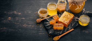 Bal ve arı ürünleri kümesi. Petek tatlım. Siyah ahşap arka plan üzerinde. Metin için özgür yer. Üstten görünüm.