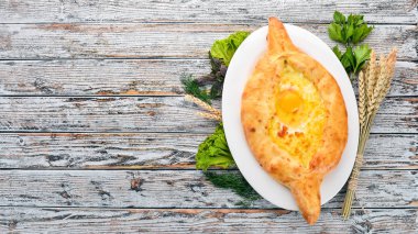 Khachapuri yumurta ve peynir ile. Gürcü mutfağı. Eski ahşap arka plan üzerinde. Metin için özgür yer. Üstten görünüm.