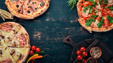 İtalyan yemeği arka plan. Pizza ürün yelpazesine. Siyah ahşap arka plan üzerinde. Metin için özgür yer. Üstten görünüm.