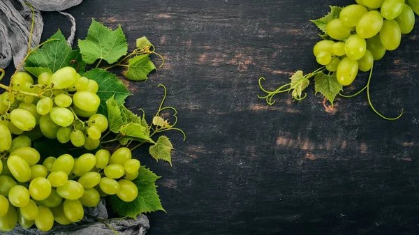Taze yeşil üzüm üzüm yaprakları ile. Üstten görünüm. Siyah ahşap arka plan üzerinde. Metin için boş alan.