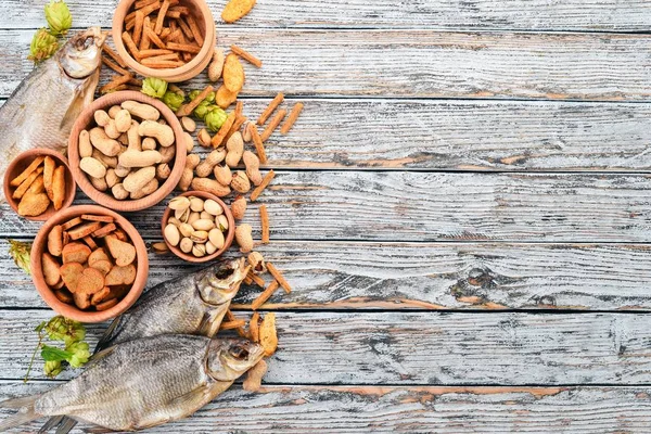 Snacks for beer. Salted crackers, Dried Fish, Chips, Nuts, Peanuts, Pistachios. On a wooden background. Free space for text. Top view.