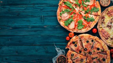 İtalyan yemeği arka plan. Pizza ürün yelpazesine. Siyah ahşap arka plan üzerinde. Metin için özgür yer. Üstten görünüm.
