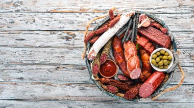 Sosis ve aperatifler mezarda ürün yelpazesine. Sosis Fuet, salam, paperoni. Beyaz ahşap zemin üzerinde. Üstten görünüm. Metniniz için boş alan.